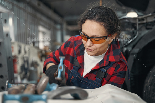 Woman car mechanic working in automobile garage