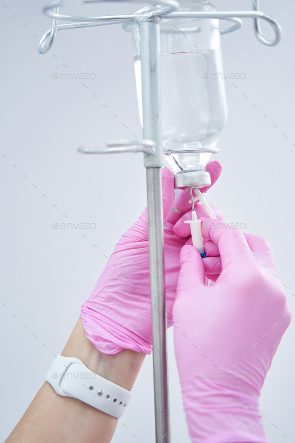 Close up photo of cosmetologist hands fixing IV infusion for client Stock Photo by Iakobchuk