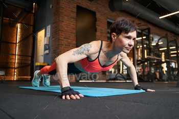 Muscular woman performing push-up on gym floor
