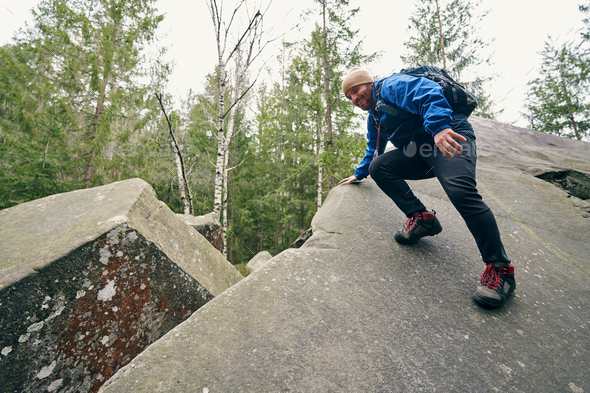 Male tourist holding rock edge while sliding down