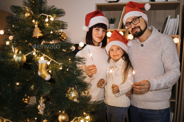 Bearded caucasian father, young mother and little cute daughter holding sparkles