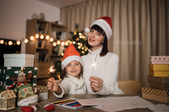 Focus on hands with sparkles, blur background of cheerful girl and her mother with charming smile