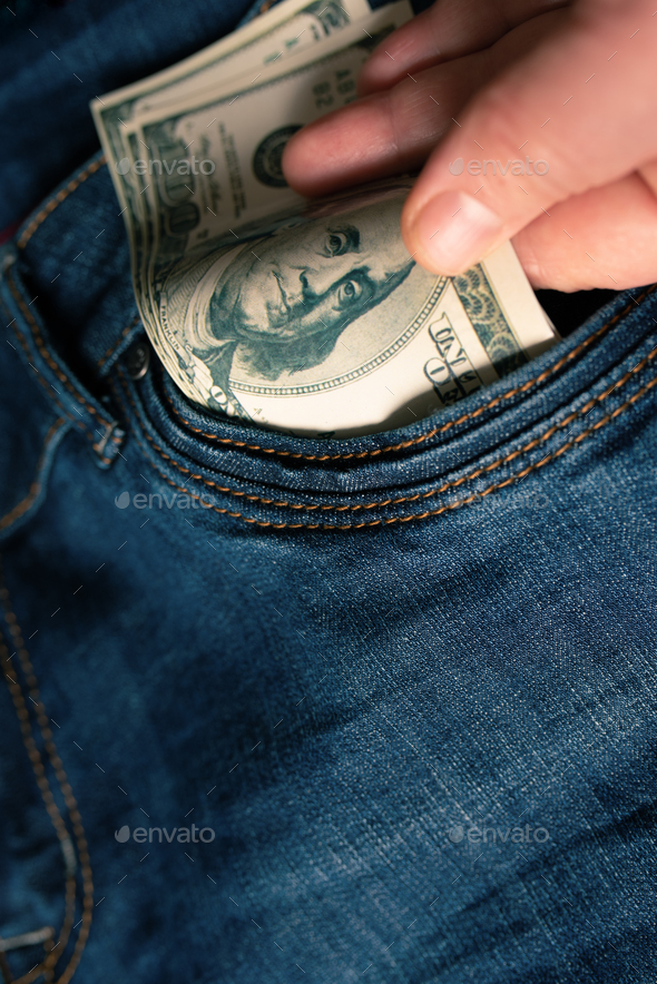 a human hand pulls money out of a jeans pocket.