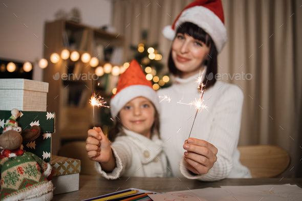 Focus on hands with sparkles, blur background of cheerful girl and her mother with charming smile