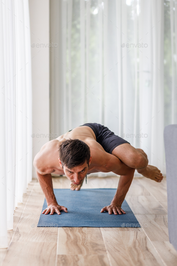 Young man doing strength pilates or yoga workout in the morning