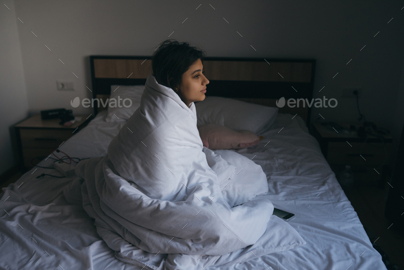 Young woman wrapped in a blanket staring into the distance
