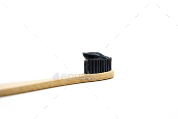 Whitening Black Charcoal Toothpaste on Bamboo Toothbrush, Close Up. 