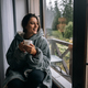 Woman holding mug, sitting on windowsill and looking at mountains - PhotoDune Item for Sale