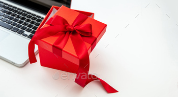 Red gift box and computer laptop on white background, close up, copy space