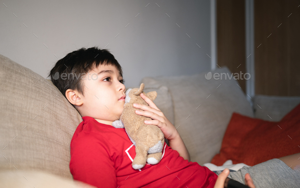 Kid sitting on sofa watching TV, APositive child lying on sofa enjoy watching cartoon on TV