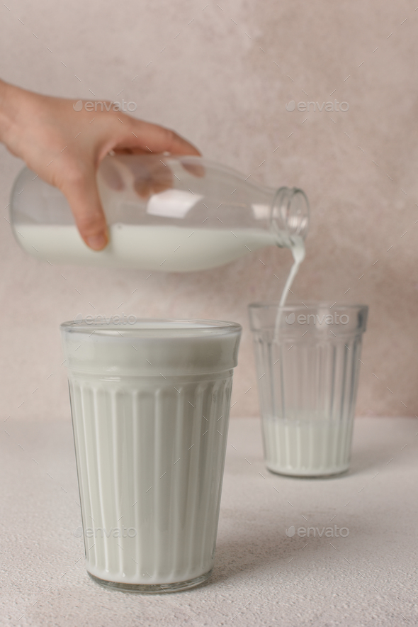 Two glasses of milk. Milk pouring from the bottle into glass. Copy