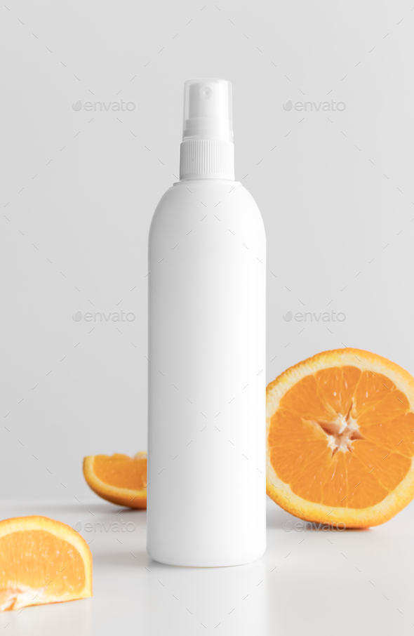 White cosmetic spray bottle mockup with oranges on a white table.