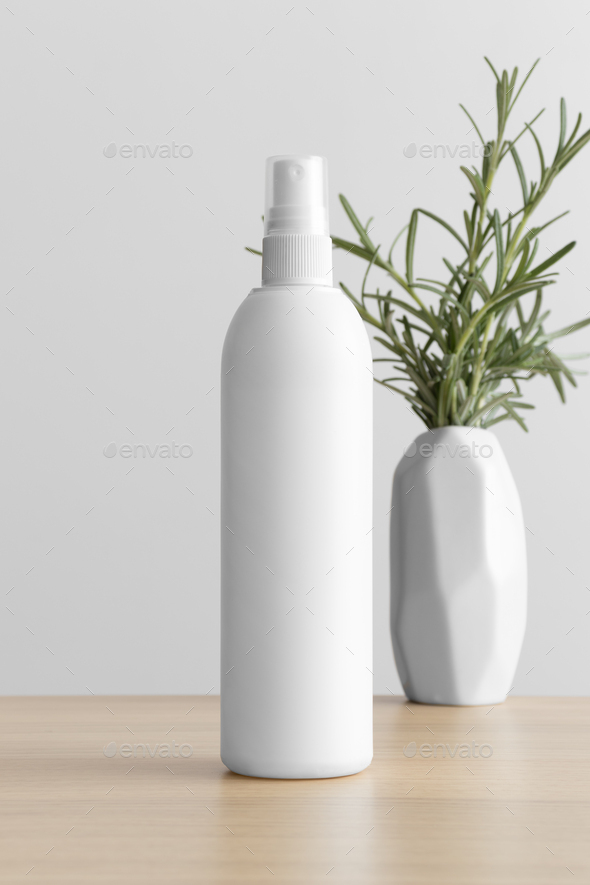 White cosmetic spray bottle mockup with a rosemary on the wooden table.