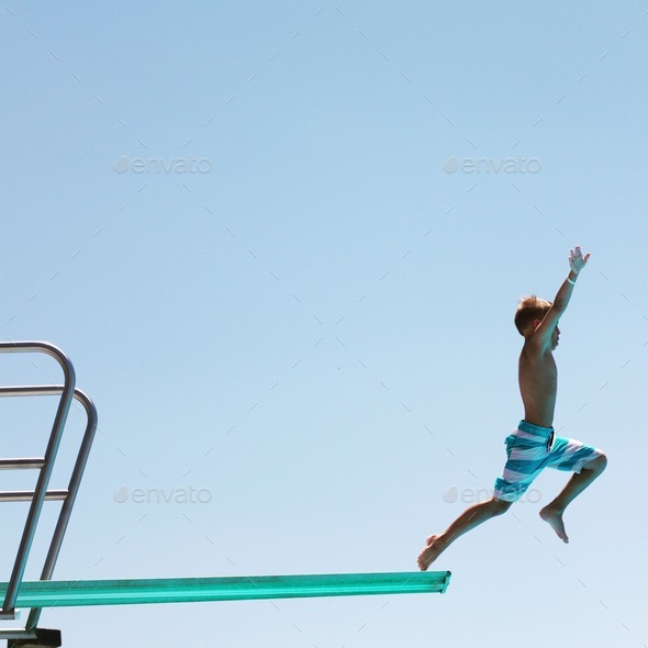 Kid jumping off the high dive on vacation at a hotel traveling with family