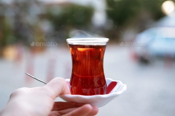 Hand golding strong black tea in traditional turkish glass cup