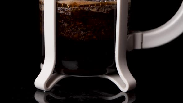 Static close up of pressing down fresh French coffee in professional studio. alt