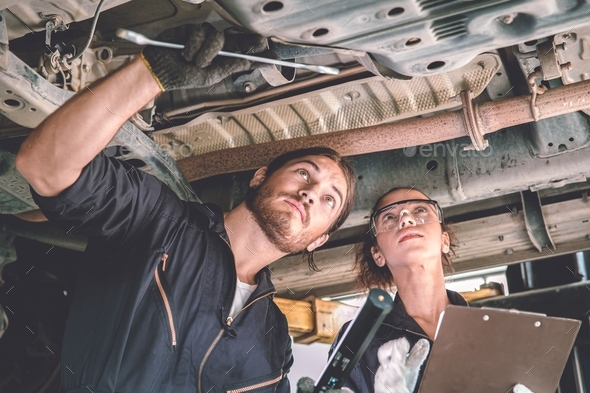 Man and woman auto mechanic working team checking under car for auto maintenance and service in gara