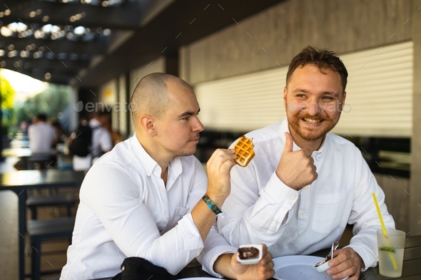Two friends eat and laugh together. Two friends having fun. Male friendship. Two friends eating.