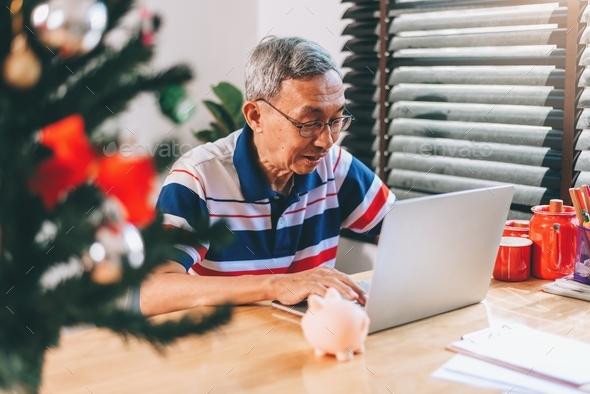 Asian senior retirement man using laptop at home living room for work and conference meeting.