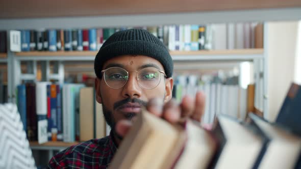 Close-up of African American Man Choosing Books in College Library Smiling alt