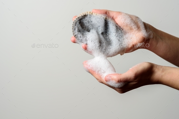 Hand holding jute wash cloth with soap foam