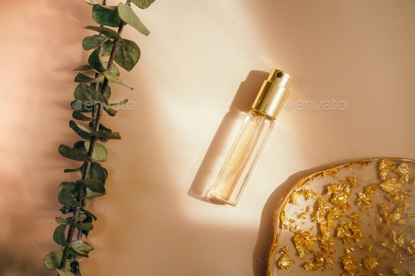 Cosmetic golden perfume mini bottle with on pastel background.