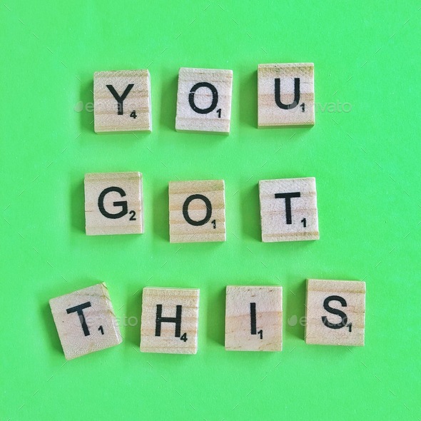 Positive motivational words written in wooden scrabbles tiles on green background
