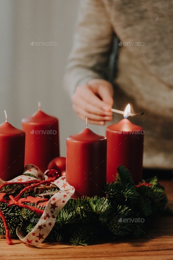 Child hand lighting first candle of Advent Wreath on first Advent