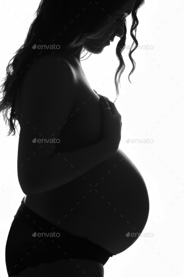 Pregnancy of young woman, profile in backlight.