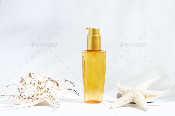 Clear bottle of yellow-orange oil for sun, tanning or hair protection. White background