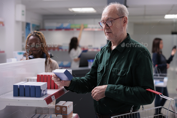 Senior man client holding shop basket in pharmacy
