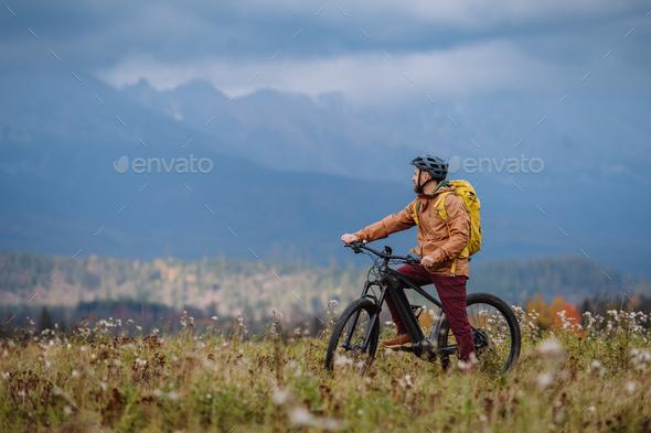 Active man on bike in the middle of autumn nature, admire mountains. Healthy lifestlye concept.
