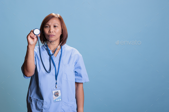 Asian medical assistant wearing blue uniform during checkup visit ...