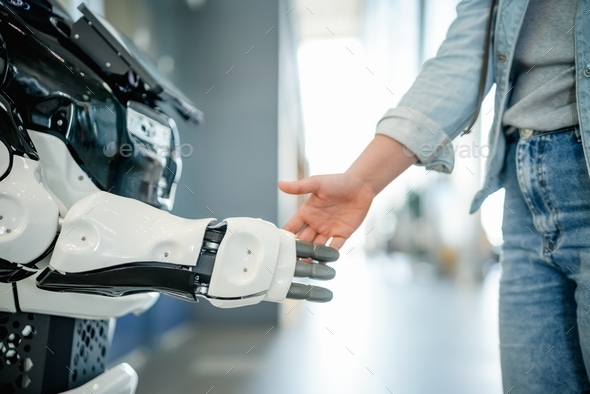 Robotic and human hands in a handshake as a symbol of collaboration, assistance and future