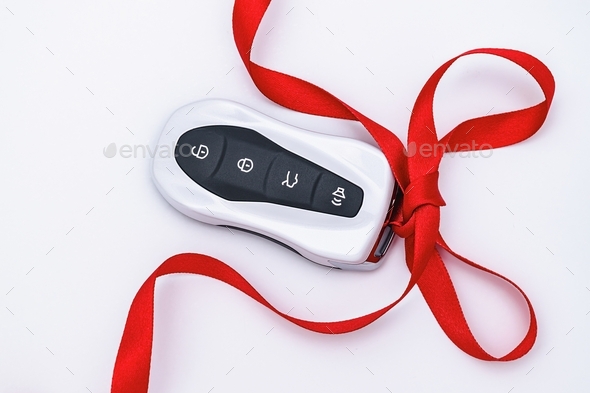Concept and gift idea. Flat lay smart car key with a red gift ribbon on a white background. Electron