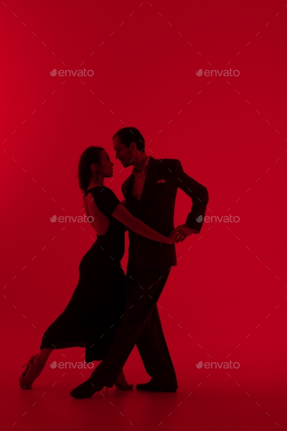 Dark silhouettes of tango dancers couple on red background.