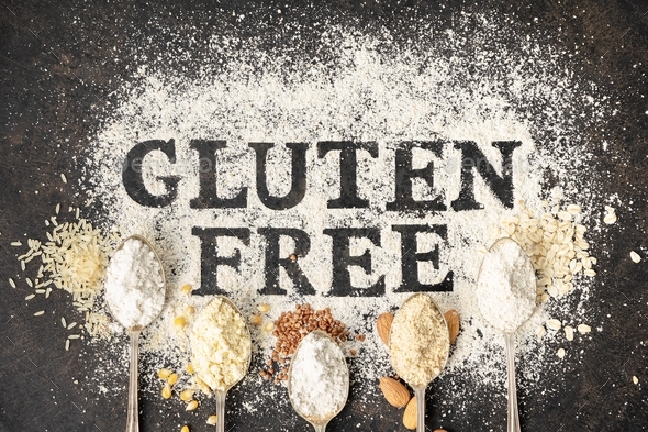 Gluten free written in flour on vintage baking sheet and spoons of various gluten free flour almond