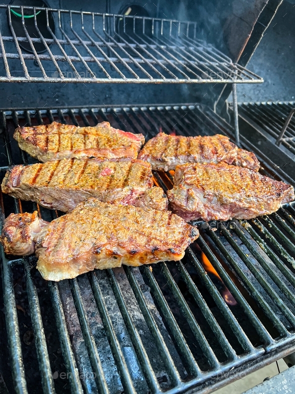 Grilling seasoned boneless New York strip steak grilling on a grill for