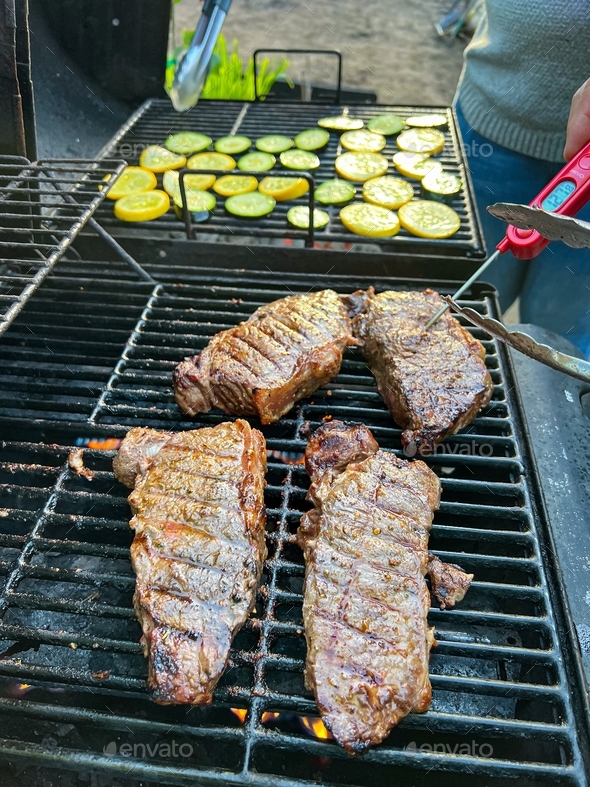 Measuring temperature on medium rare New York Strip Steak on grill with