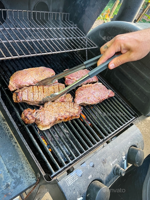 Grilling seasoned boneless New York strip steak grilling on a grill for