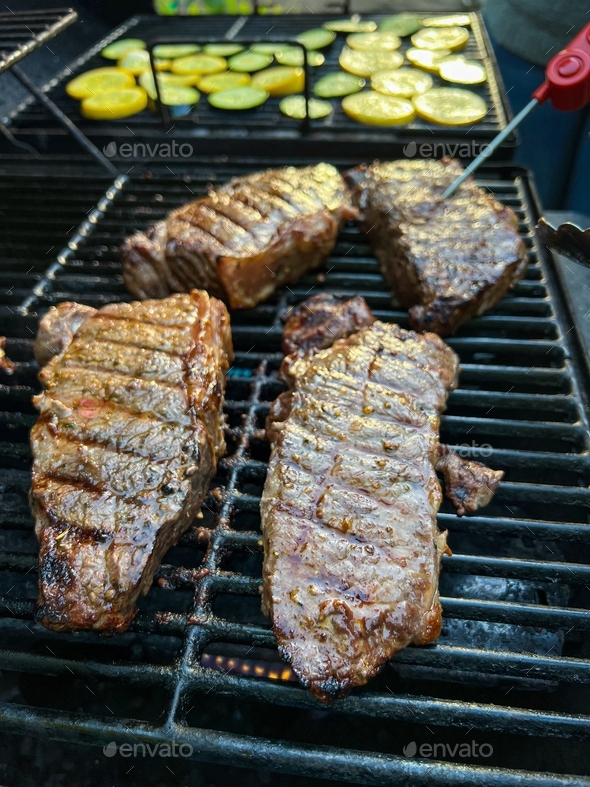 Measuring temperature on medium rare New York Strip Steak on grill with