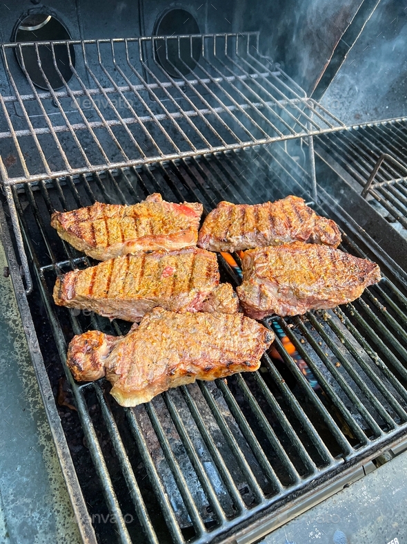 Fresh seasoned boneless New York strip steak grilling on a grill for a