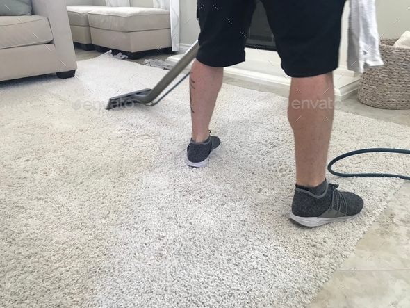 A man is shampooing a white rug to remove stains and keep it clean