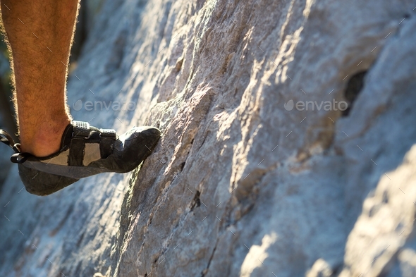 Climbing shoes on the climber\'s foot rest the toe on the rock. Extreme sports, mountain tourism.