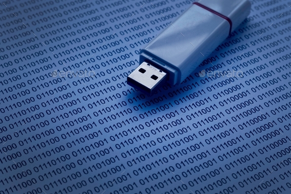 Selective focus of usb drive on a paper of binary code.