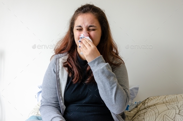 latin woman feeling sick, pain, illness, sneezing using tissue to cover