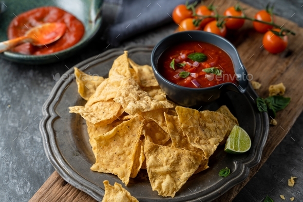 Traditional Mexican appetizers of hot crispy nachos with tomato salsa ...