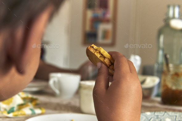 elementary age boy eating cookies on breakfast table - Stock Photo - Images
