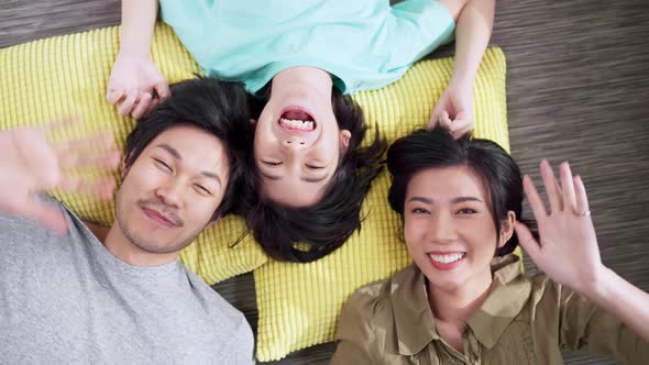 Happy Asian family mom dad and boy male kid child laying laugh smile on big yellow pillow