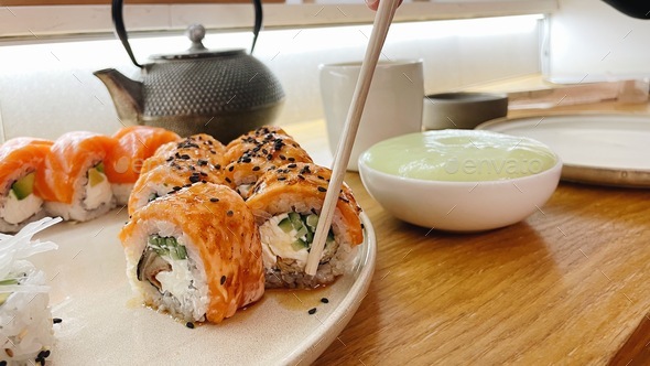 eating sushi rolls with salmon by food sticks at the restaurant. Asia food.Serving food.Wasabi sauce